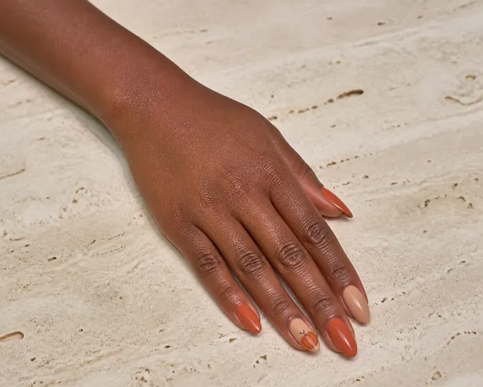 Tiny pumpkin accent cute fall nails on a warm nude base
