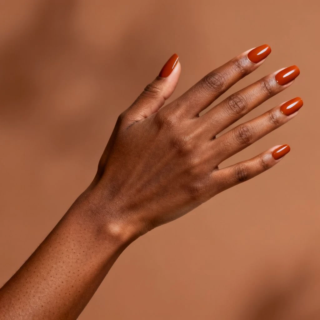 Glossy terracotta Thanksgiving nail colour in a hand-only close-up