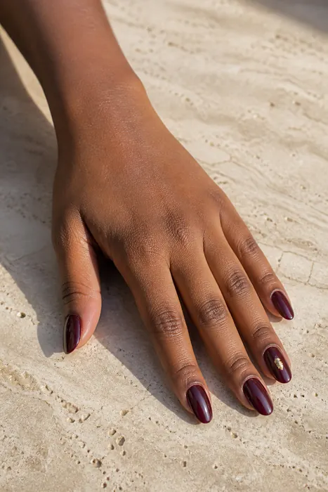 Burgundy glazed chrome fall nails with a gold foil accent
