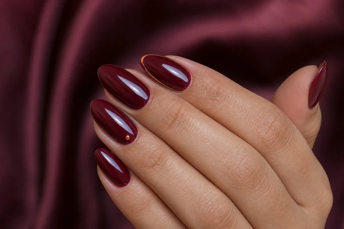 Cranberry almond nails with a refined copper halo detail
