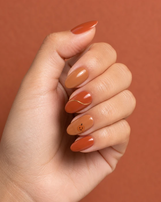 Cute terracotta Thanksgiving nails with a tiny smiling pumpkin