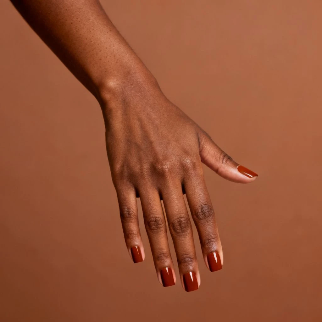 Short Square Rust short autumn nail design on a woman’s hand.