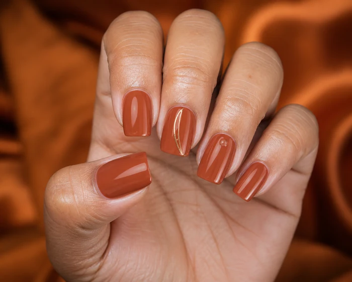 Terracotta nails with a clean negative-space gold curve