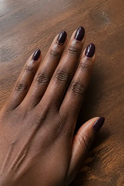 Deep plum oval nails with fine gold crescent accent