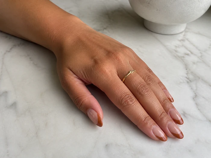Caramel French tip press-on nails on a marble table