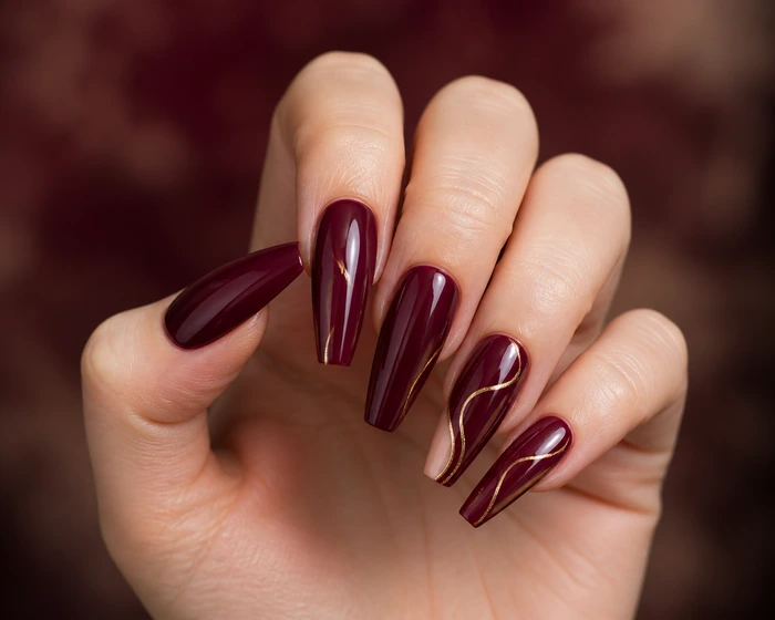 Long wine coffin acrylic nails with negative-space gold curves
