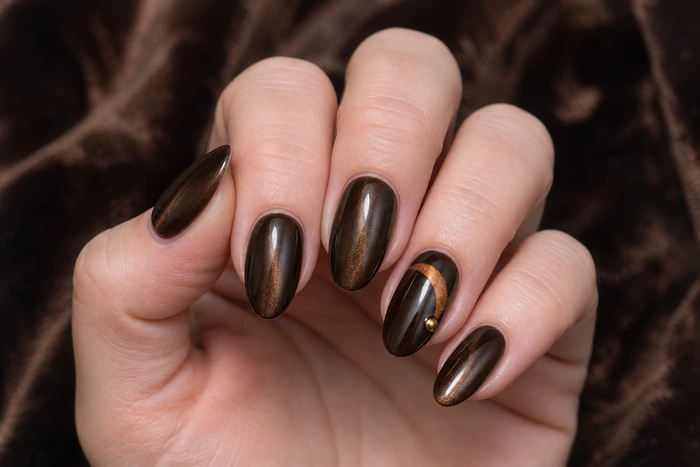 Deep cocoa cat-eye nails with amber metallic arc