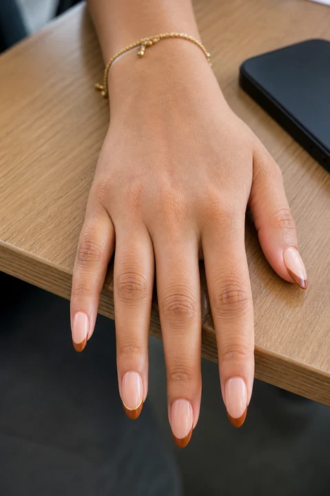 Long almond nails with caramel brown French tips and a fine gold line