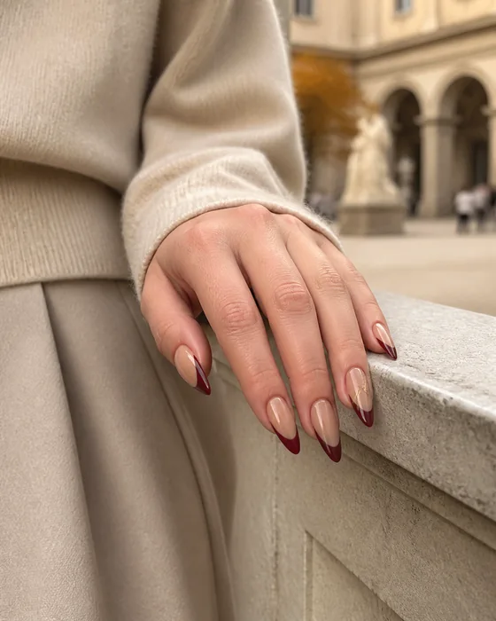 Burgundy French tip fall stiletto nails on a stone ledge