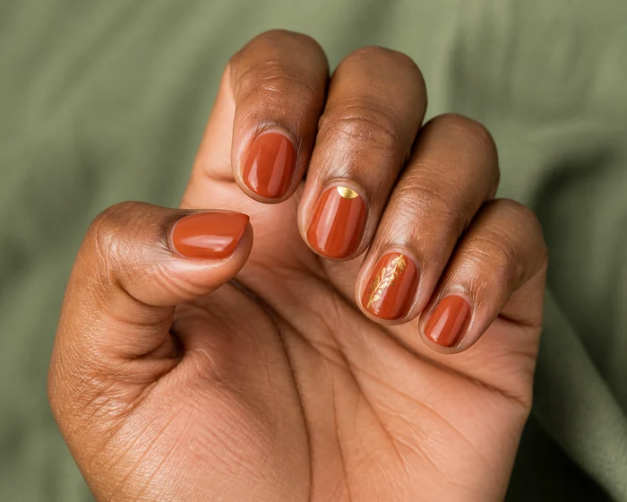 Short cinnamon nails with a gold leaf accent