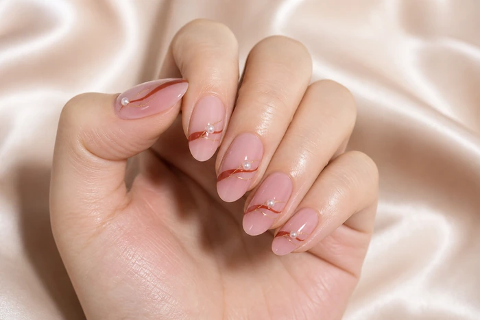 Soft pink nails with rust ribbon detail and pearl finish