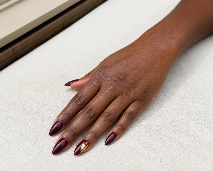 Long burgundy Gel-X extensions with a gold foil detail