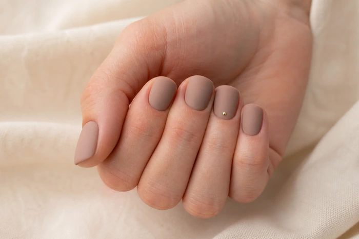 Short latte matte nails with a subtle gold dot accent