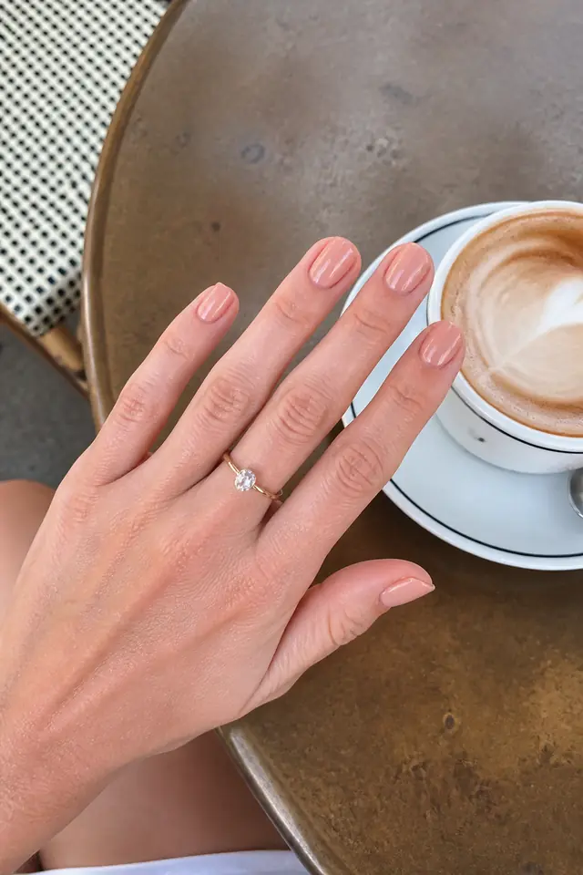Short Warm Nude short autumn nail design on a woman’s hand.