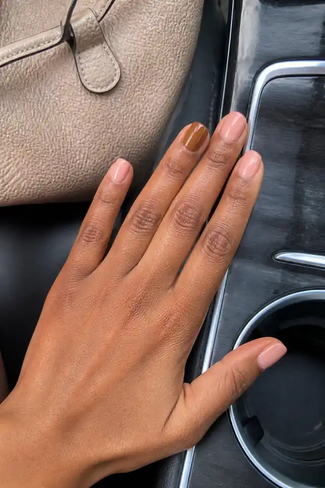 Short natural nude nails with one caramel accent finger.