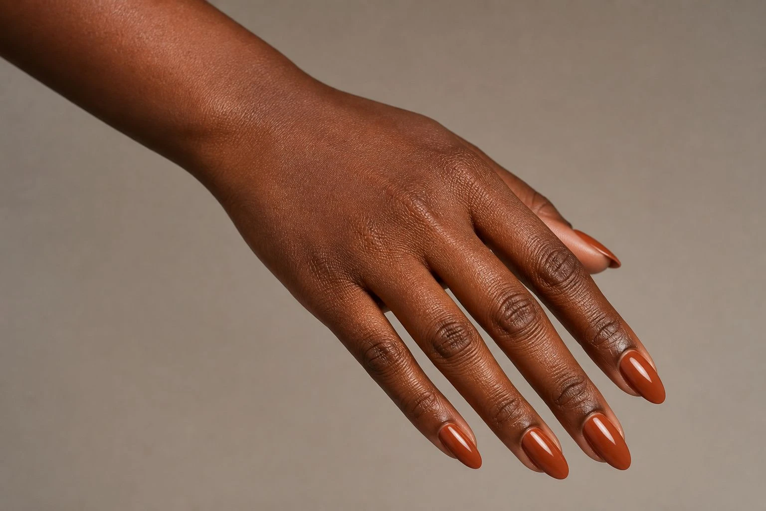 Cinnamon Almond autumn nails on a woman’s hand, almond shape, hand-only studio macro shot.