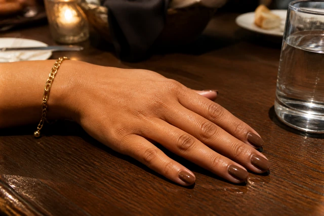 Soft Square Mocha autumn nails on a woman’s full hand in a natural setting.