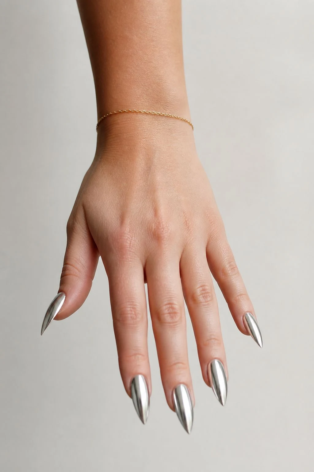 Silver Chrome Stiletto baddie Christmas nails with a delicate gold bracelet