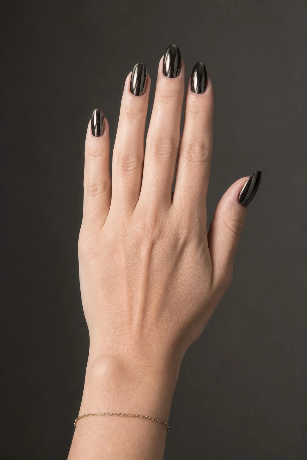Black chrome oval Christmas nails with a delicate gold bracelet