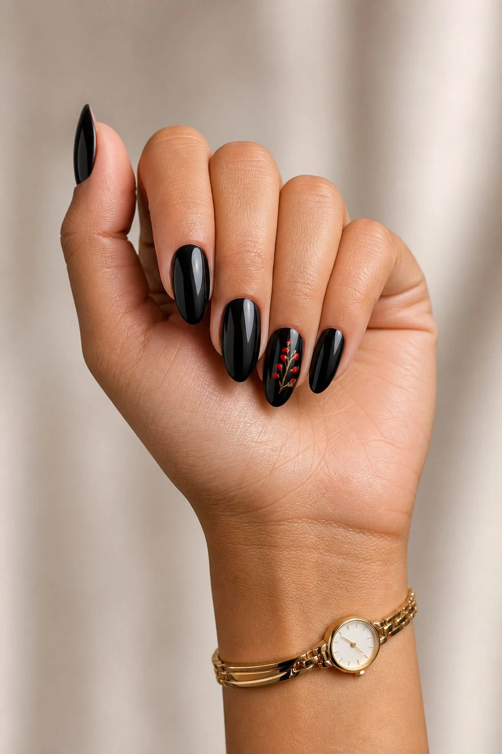 Black Christmas nails with a red berry accent in a curled hand pose with a delicate gold watch