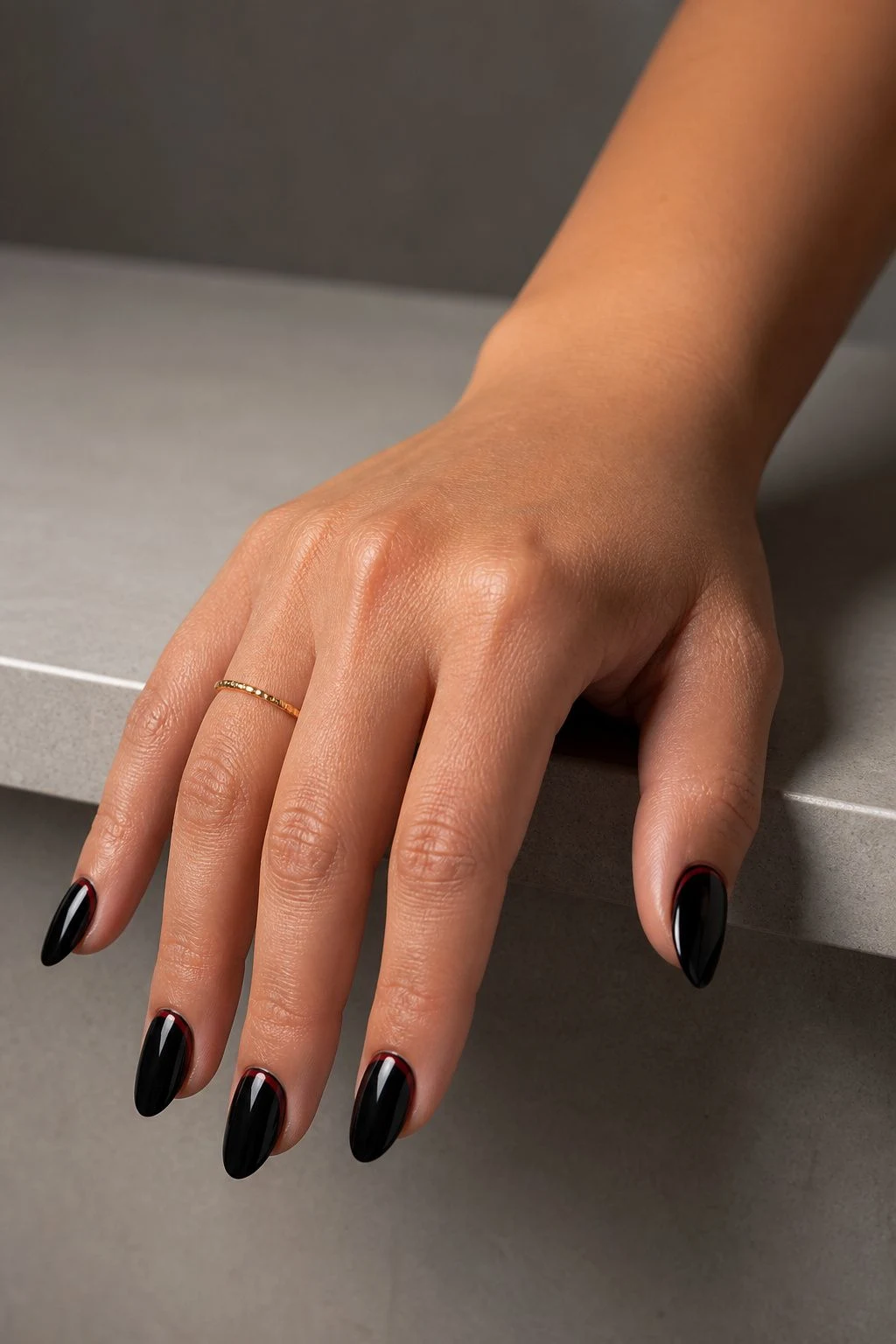 Black nails with delicate deep-red lines and a delicate gold ring