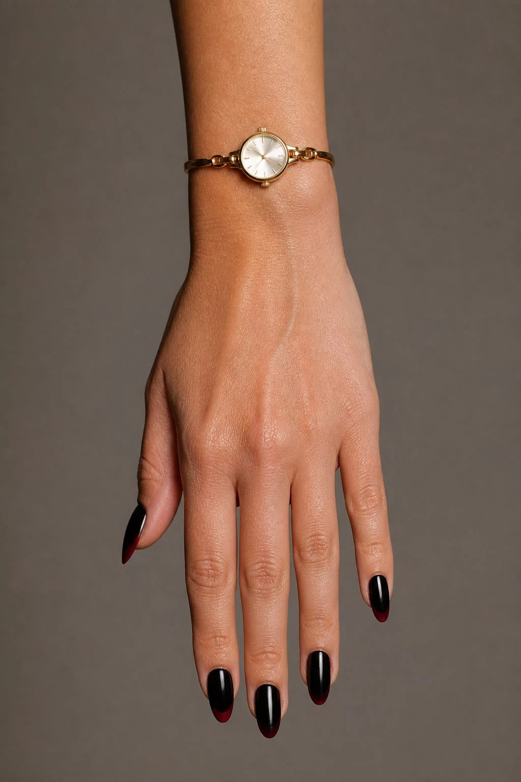 Black nails with a deep red French accent and a delicate gold watch