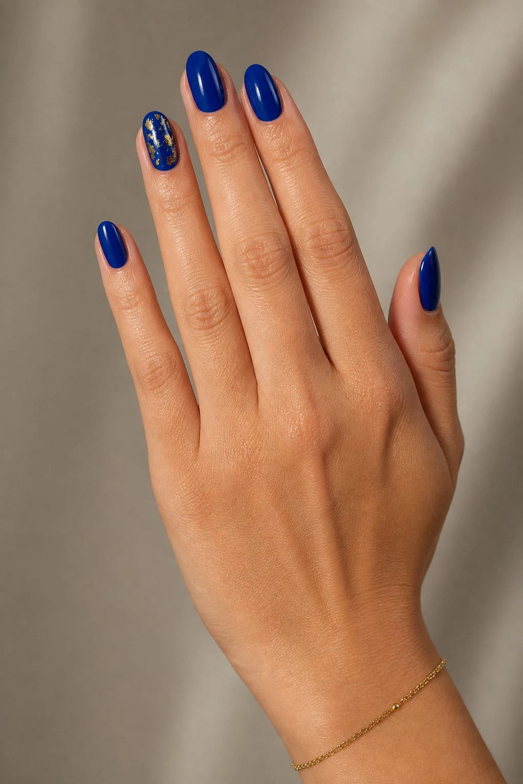 Sapphire Gold Foil baddie Christmas nails with a delicate gold bracelet