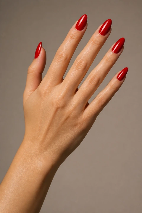 long bright red glossy almond extensions on a light brown hand with visible wrist