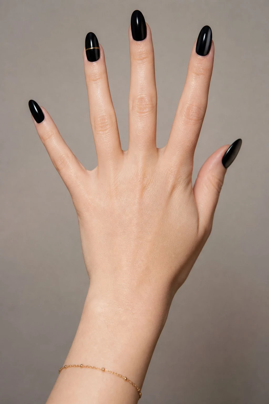 Black Christmas nails with a refined gold accent and a delicate gold bracelet