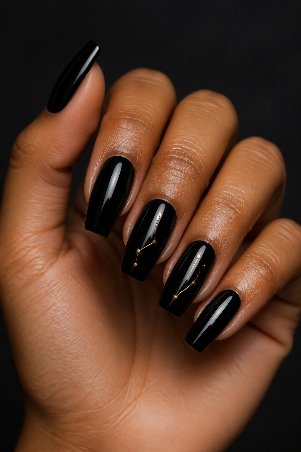 Glossy black Christmas nails with a fine gold constellation accent.
