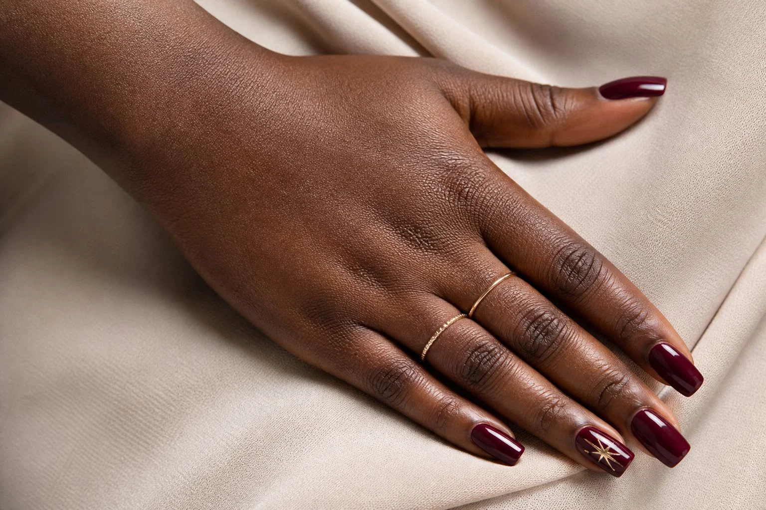 Long burgundy square Christmas nails with a delicate gold star accent nail, hip resting pose