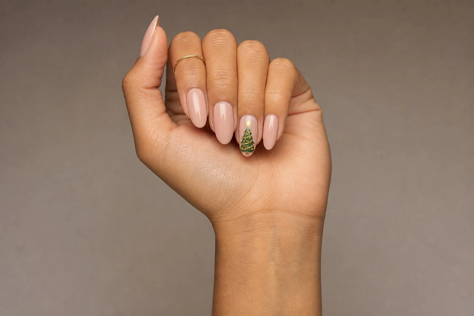Gel Christmas Tree Accent nail art in a curled hand pose with a delicate gold ring