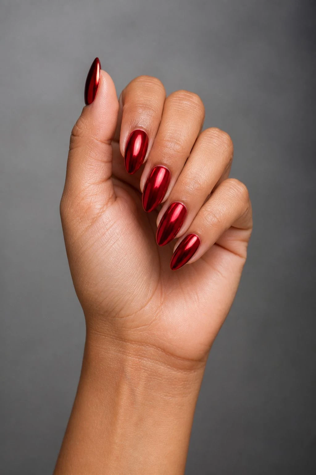 Cherry Red Mirror Chrome Christmas nails in a curled hand pose with thumb clearly separated