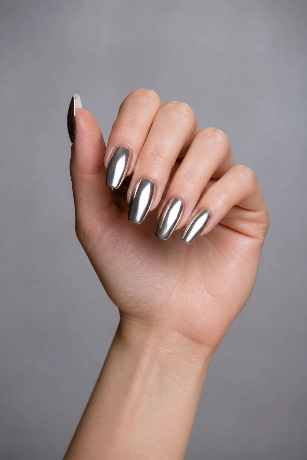 Long Silver Chrome Coffin Christmas nails in a curled hand pose with thumb clearly separated