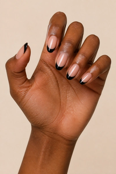 Black French tip nails on a deep brown skin tone hand in a relaxed side angle with visible wrist and short partial forearm, natural daylight