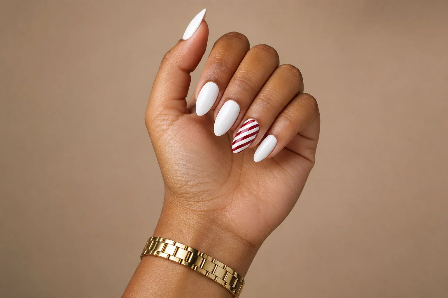 Curled hand showing a glossy white almond manicure with a red and white candy cane striped accent nail and a slim gold watch