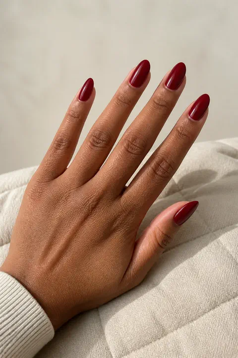 dark cherry red French tip almond nails on a tan hand with visible connected wrist