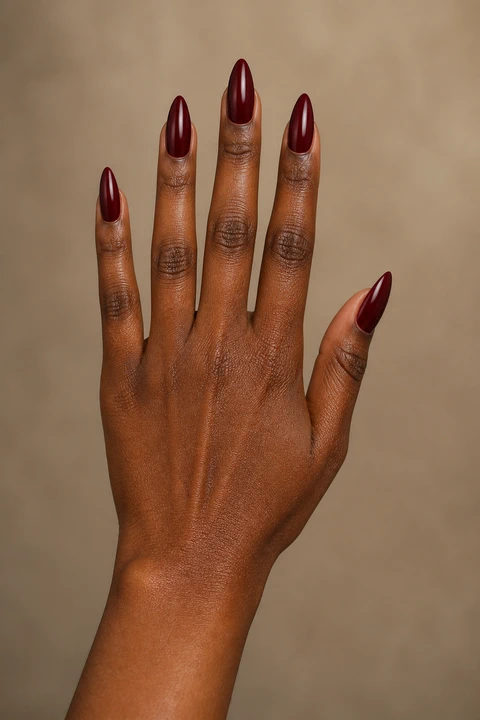 long dark cherry red glossy almond extensions on a medium brown hand with visible wrist and forearm