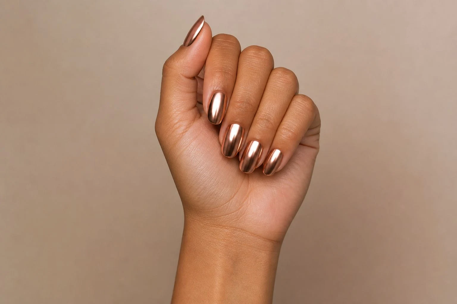 Warm chrome metallic nails in a curled hand pose showing all five fingers