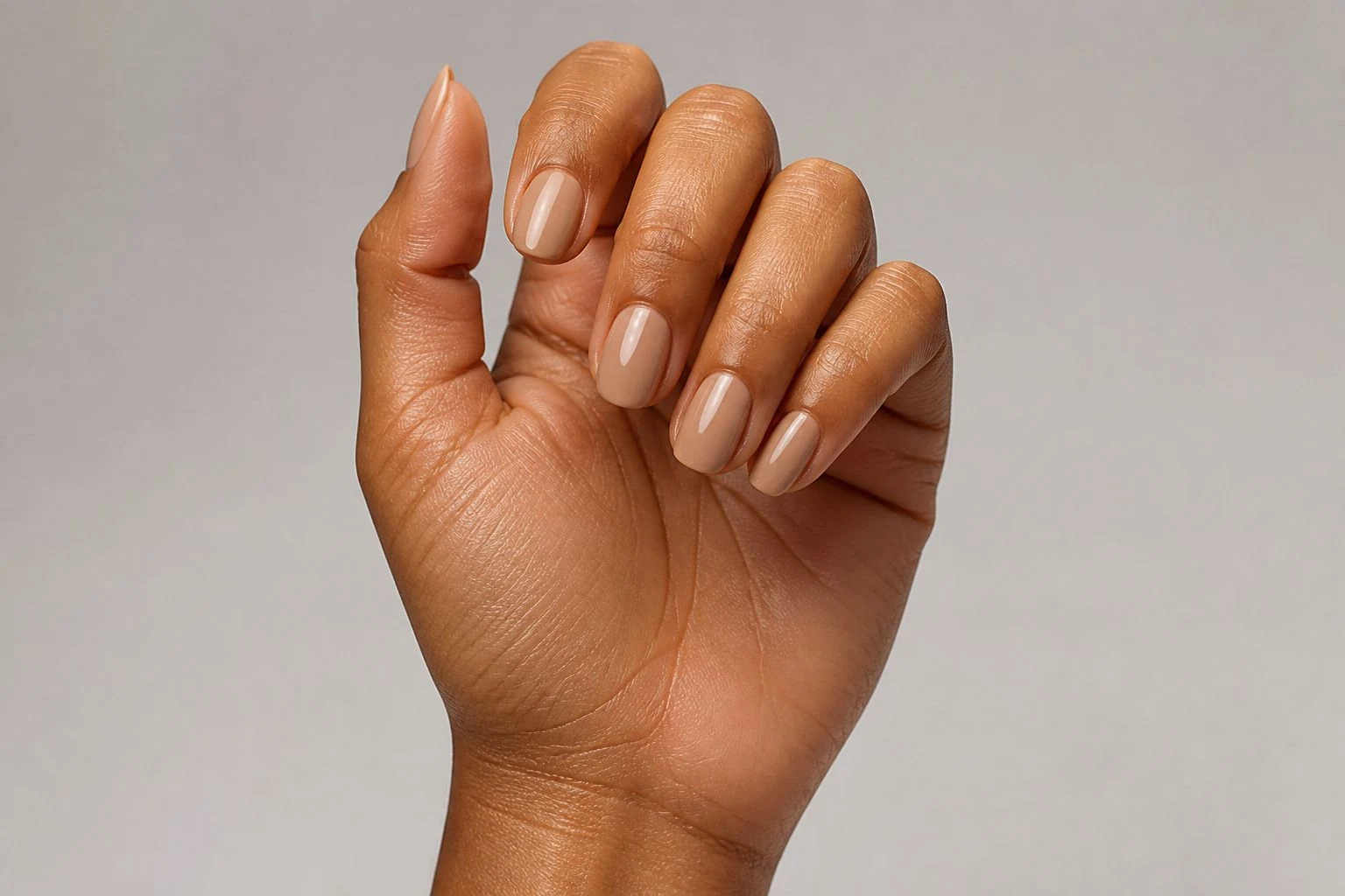 Glazed beige donut shine nails in a tilted curled hand pose