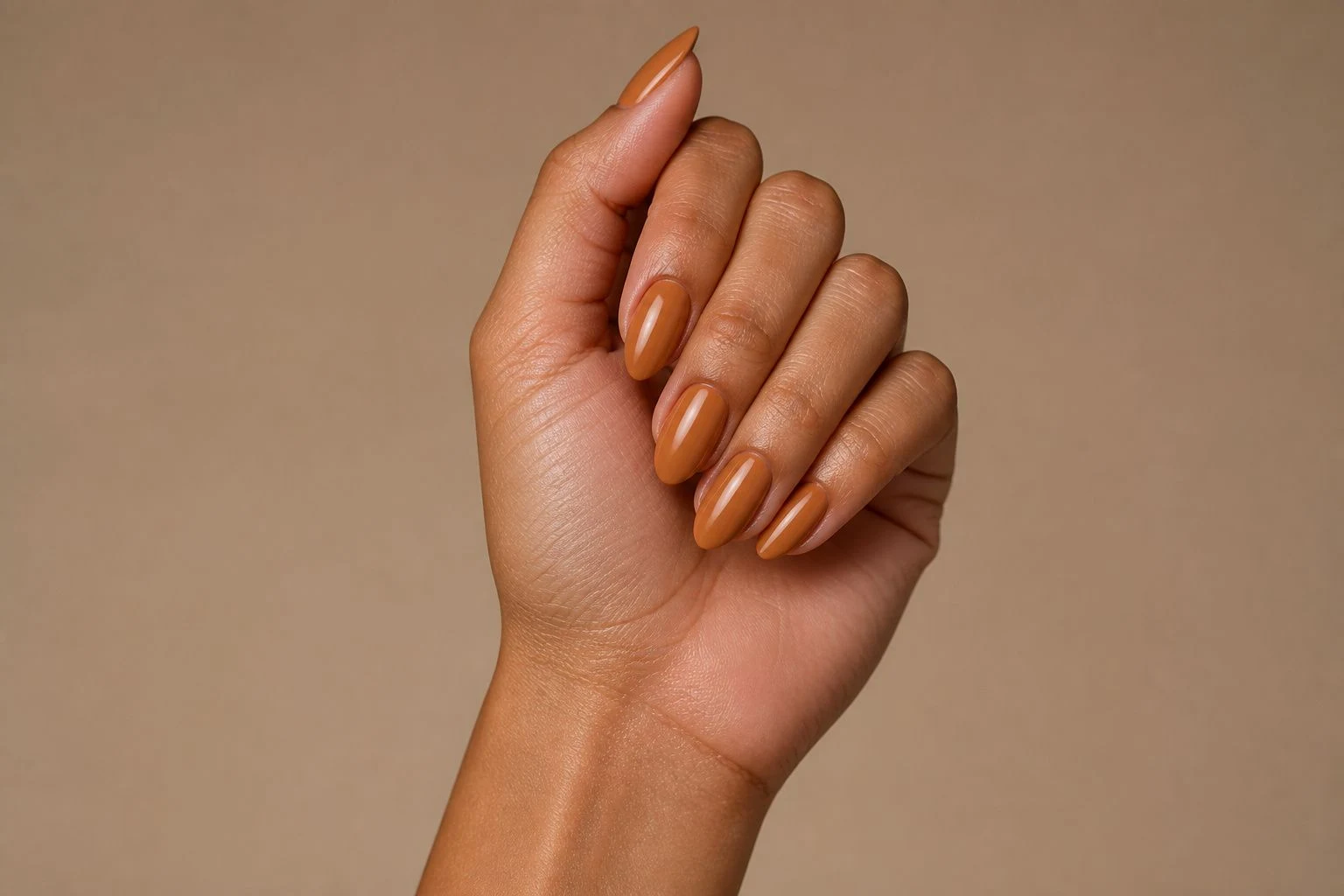 Long caramel almond nails in an elevated curled hand pose showing all five fingers