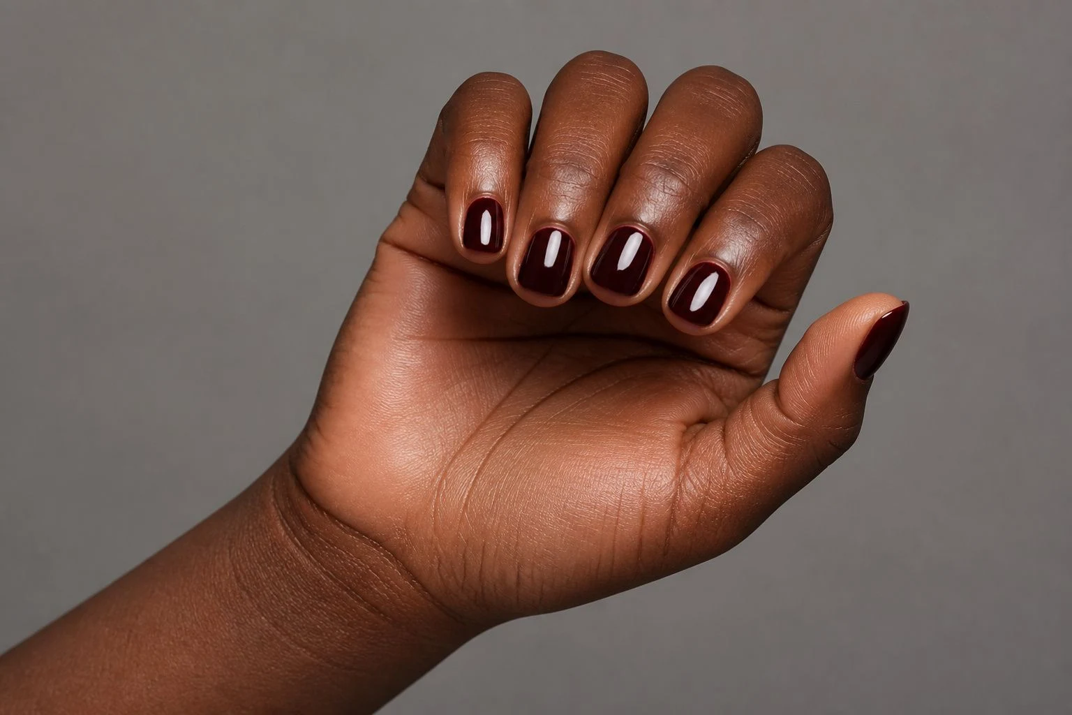 Oxblood date night nails in a curled hand pose with thumb clearly separated