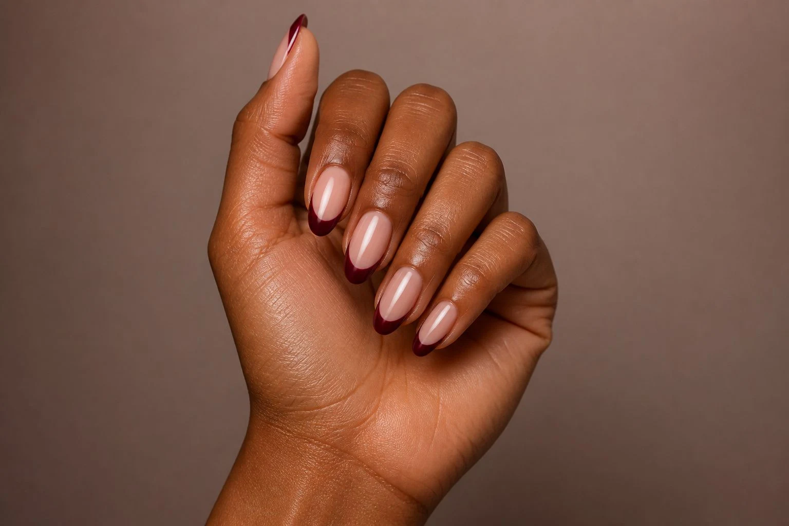 Elegant burgundy french tip nails in a tilted curled hand pose