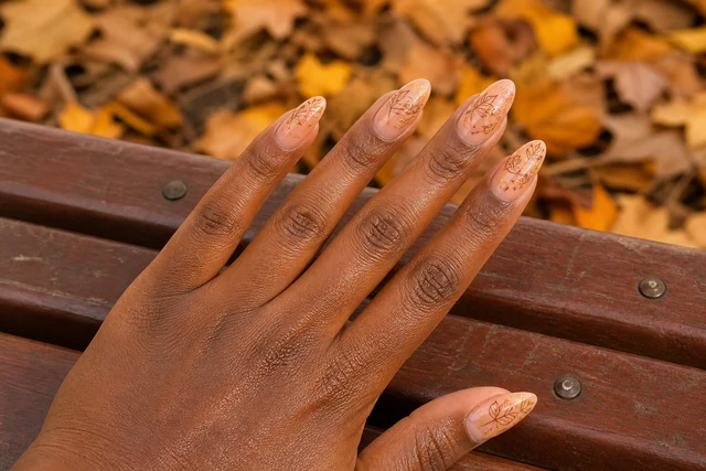 21 leaf art fall nail inspo on a woman’s full hand.