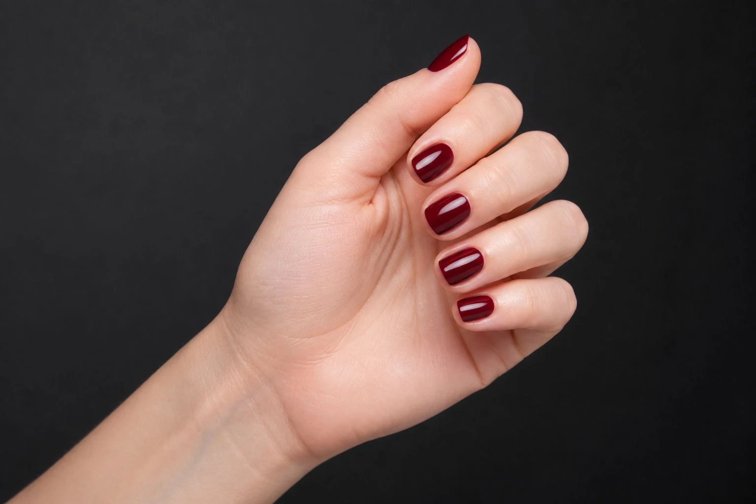 Deep burgundy round nails in a soft curled hand pose showing all five fingers