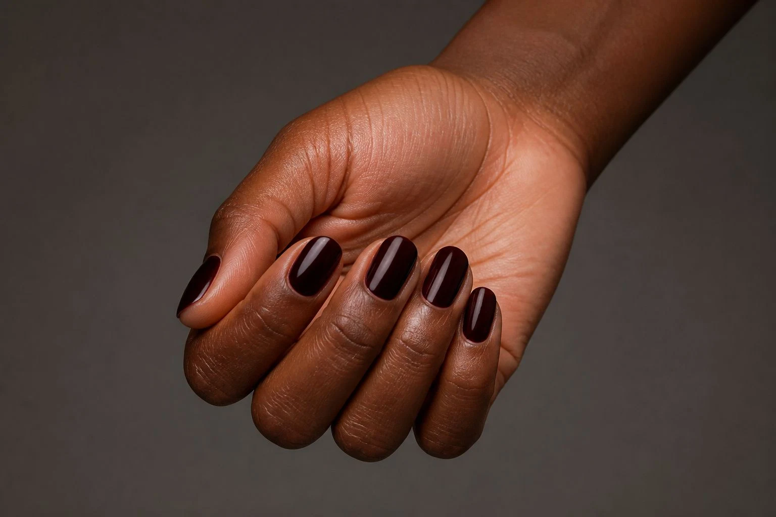 Oxblood round nails in a curled hand pose with nail tops facing the camera