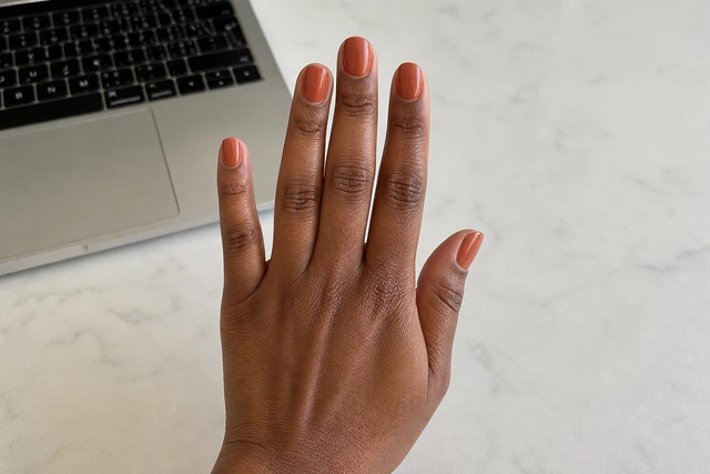 Terracotta fall nails on a woman’s complete hand in a natural everyday setting.