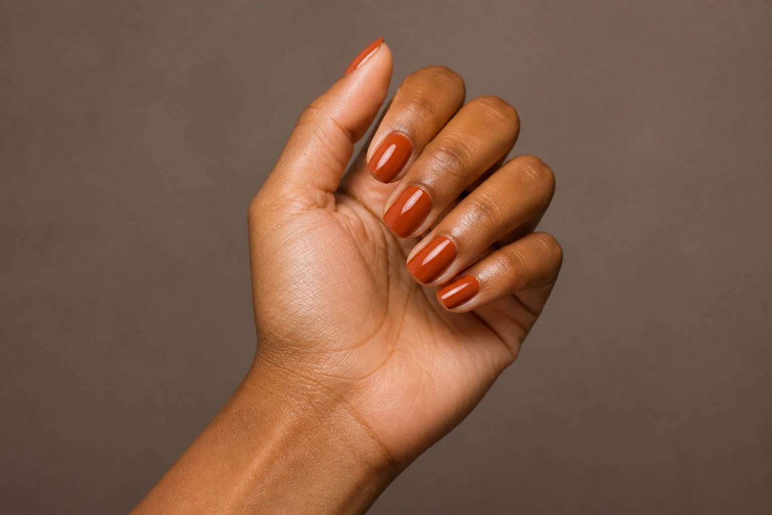 Rust orange brown square nails in a soft curled hand pose