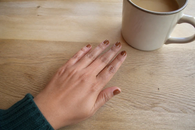 Caramel fall nails on a woman’s complete hand in a natural everyday setting.
