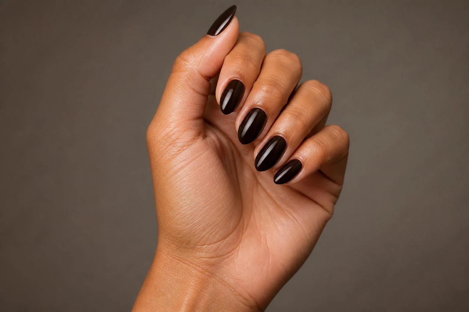 Deep chocolate brown almond shaped nails in an elevated curled hand pose